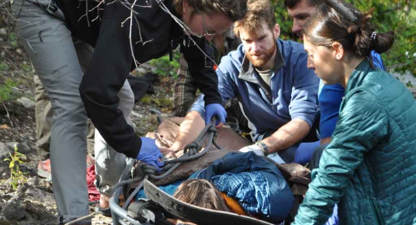 four people participate in a wilderness first responder exercise